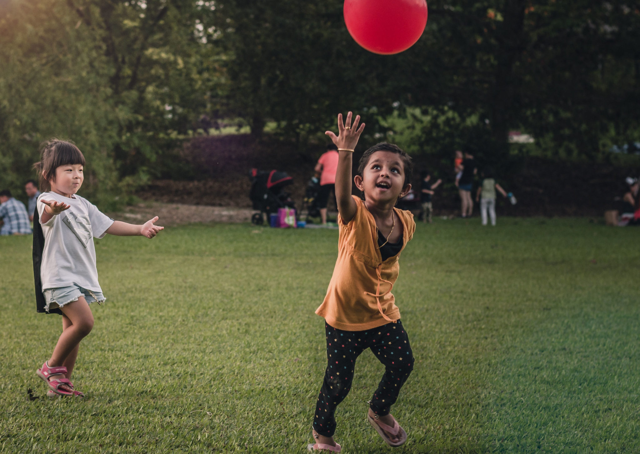 Two girls playing with balloon on lawn (740x525)