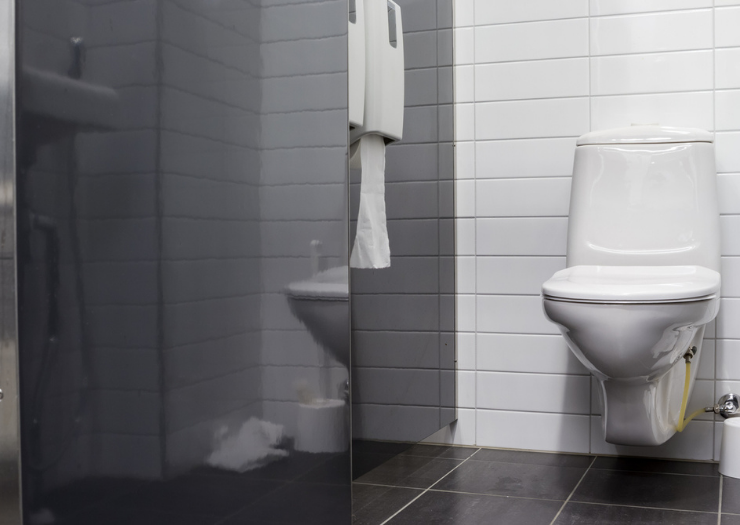 A white toilet in a black bathroom stall.