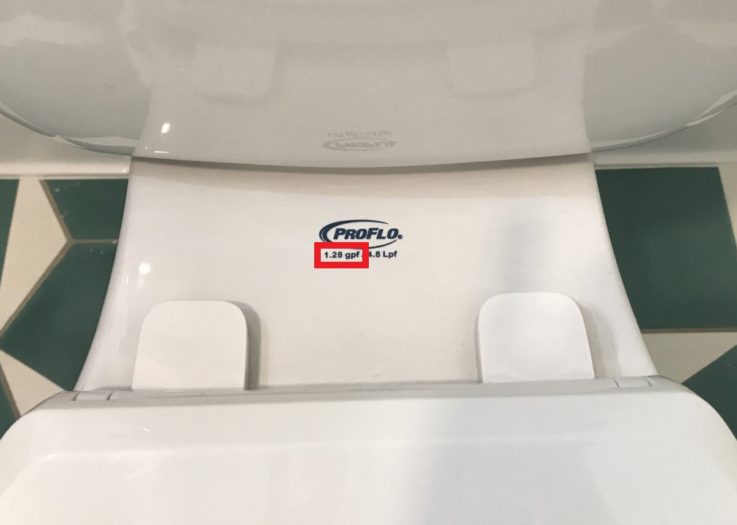The back of a toilet seat showing where the gallons per flush and toilet brand is stamped.