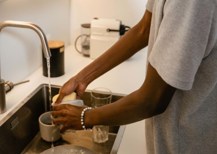 African American man washes dishes in the sink at home. 